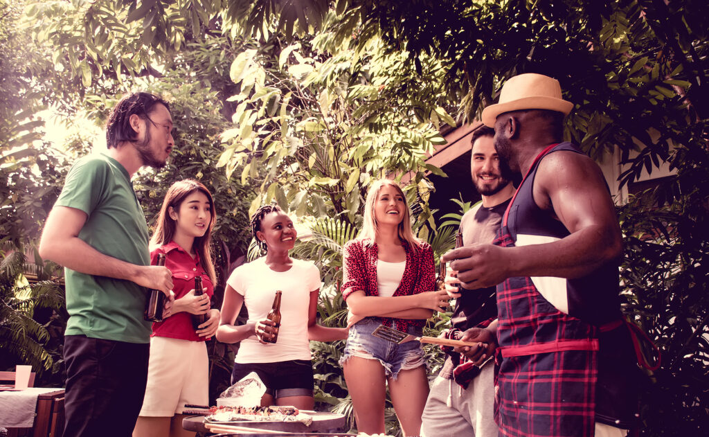 Group of friends outside in summer having a tailgating BBQ party with food and drinks