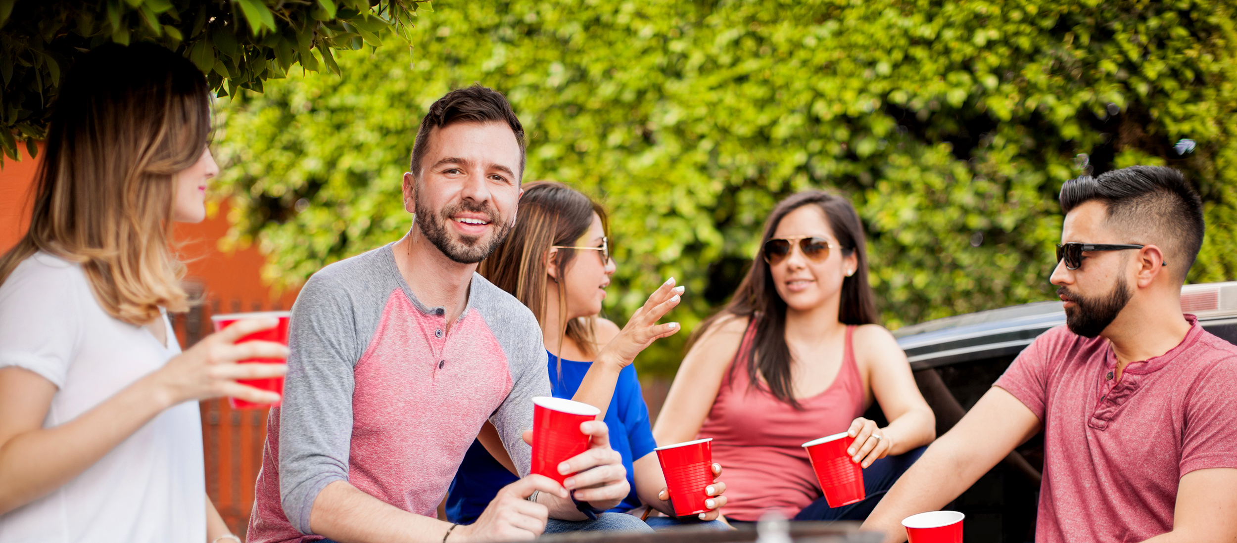 Group of friends having a tailgating BBQ outdoors in summer